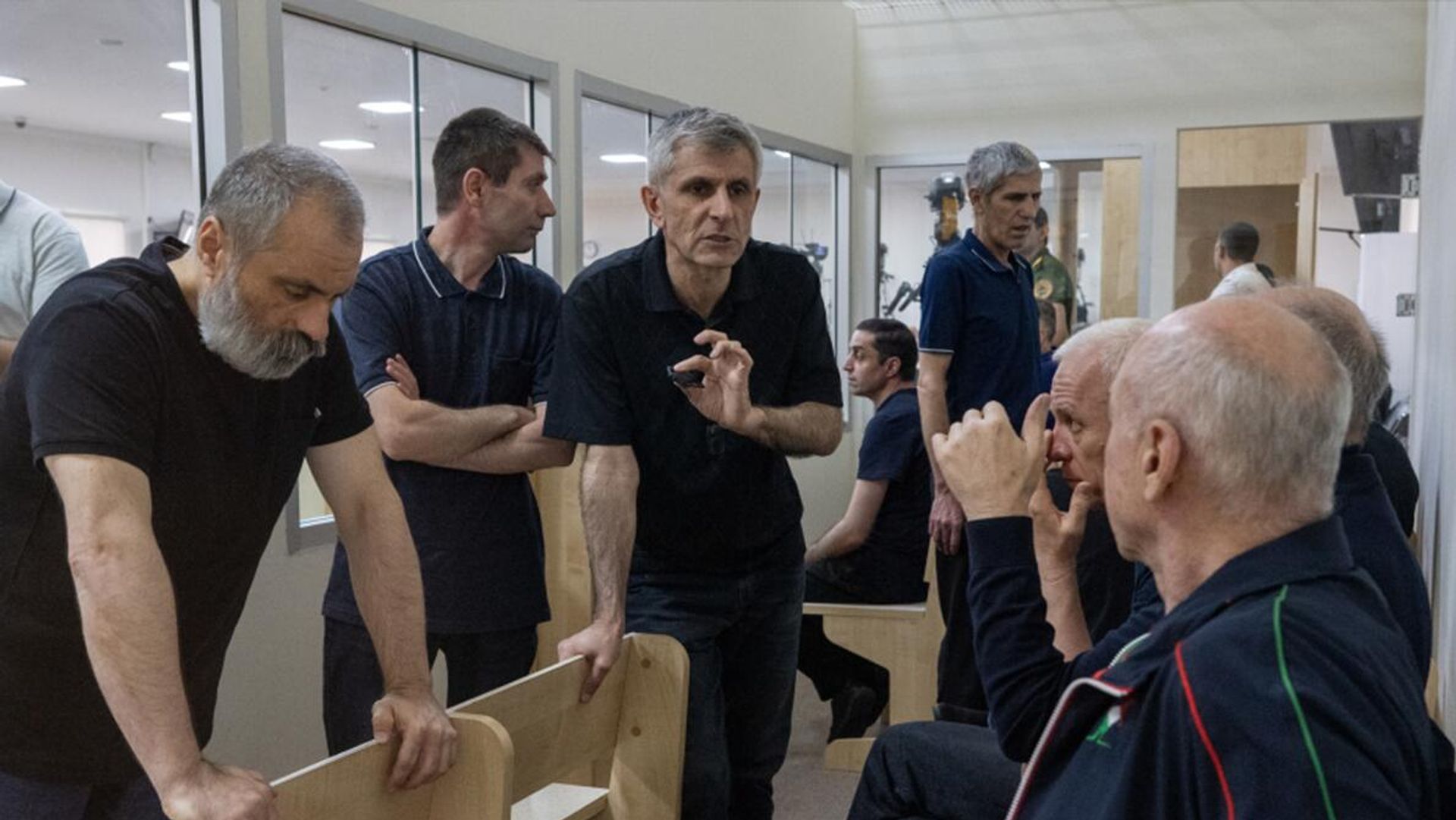 Armenian leaders and prisoners held in Azerbaijani custody speak together inside a courtroom in Baku.